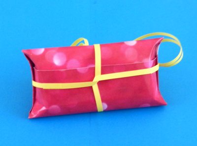 papercraft ribbon around a pink origami gift box