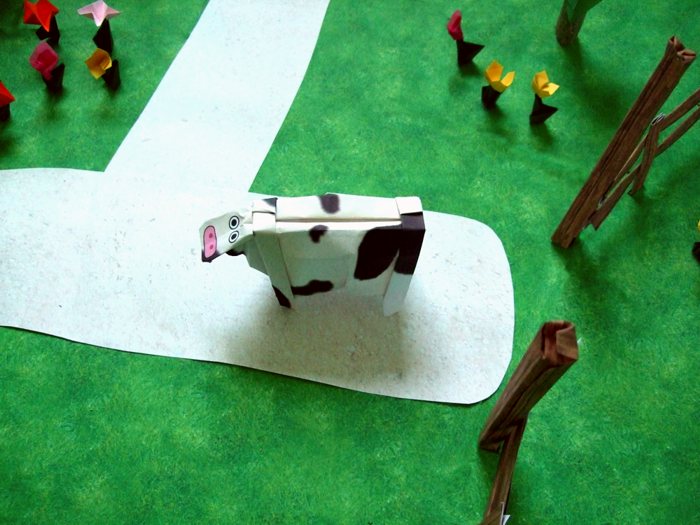 origami cow walking on a path