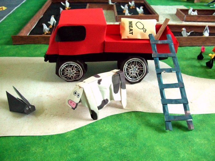 cow standing next to a large kirigami pick up truck