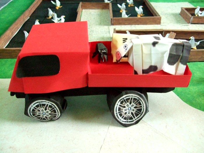 cow standing on a kirigami pick up truck