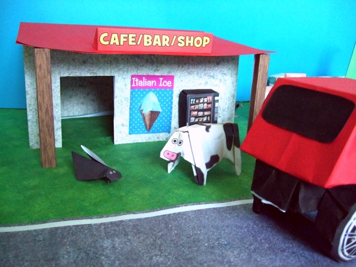 cow and a bug in front of a kirigami road shop