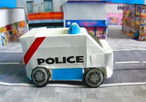 Card with a papercraft cop car in the city