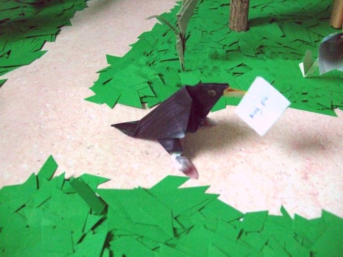 origami birdie walking on a path in the forest