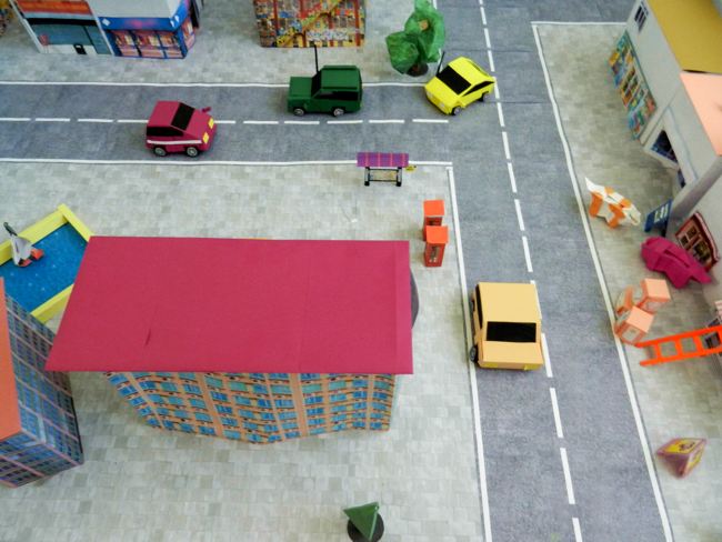 kirigami cars riding through a papercraft town