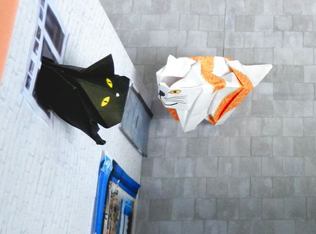 origami black cat talking to another folded cat