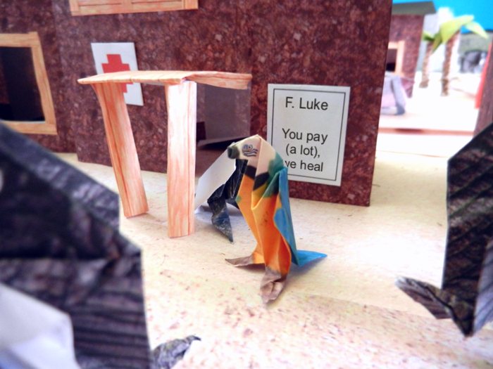 origami parrot in front of a folded doctors house