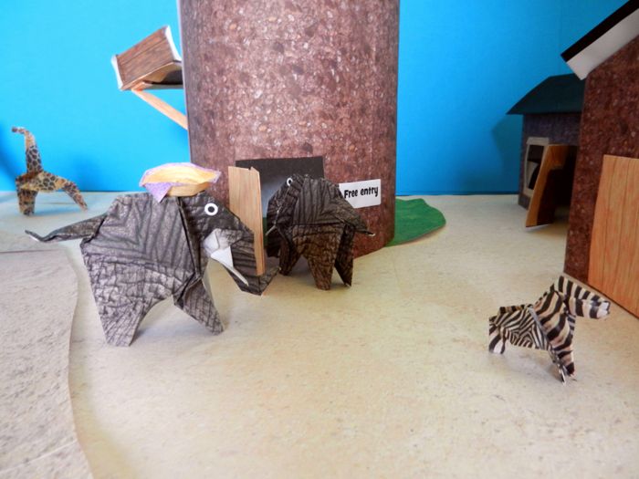 origami elephant entering a large kirigami tower