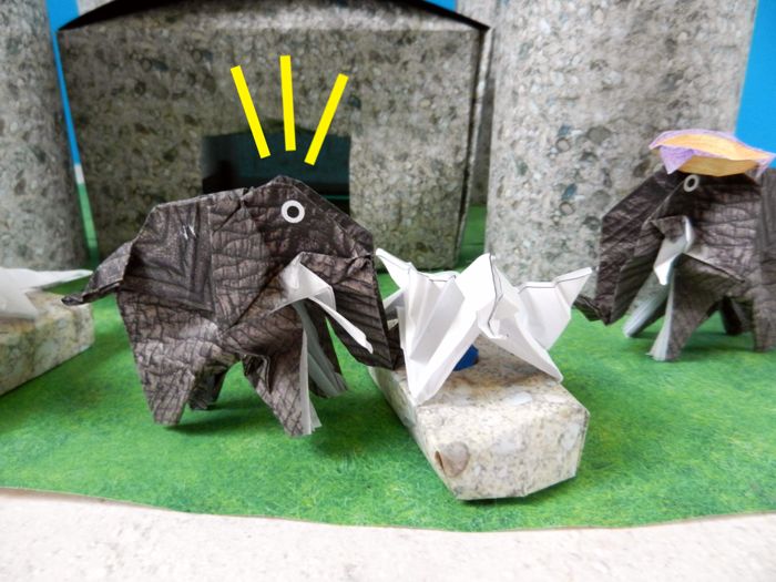 paper elephant pushing a dragon statue aside